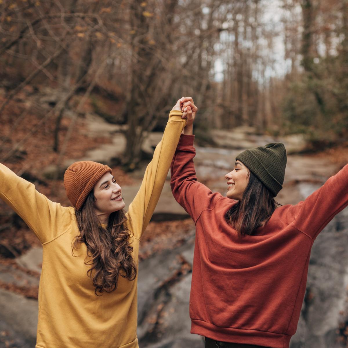 2 friends holding their hands in the air smiling at each other
