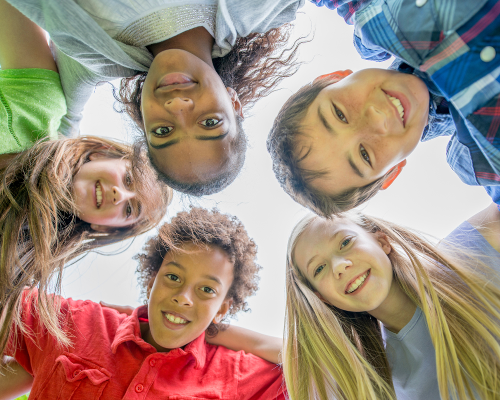 5 children looking down into a camera while standing in a circle