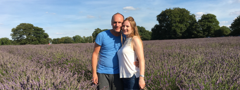 Traveling couple smiling and standing in a field of flowers