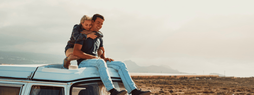 Couple hugging on a car rooftop 