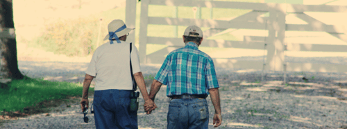 Empty-nester couple holding hands and walking turned away from the camera