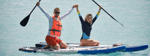 Couple on paddle boards holding hands up