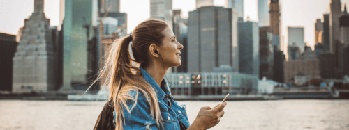 Woman walking in a city while holding her phone