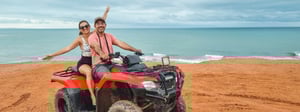 Couple riding a 4-wheeler along a coastline