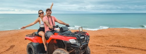 Couple riding a 4-wheeler along a coastline
