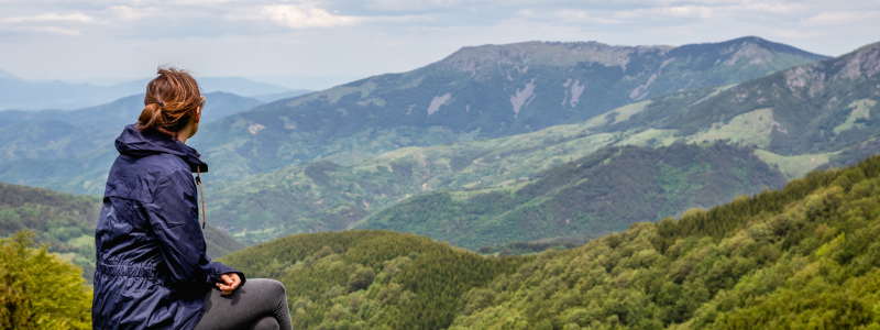 Woman sitting on a beach looking into a mountain range
