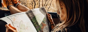 Woman looking at a map with her feet out a car window
