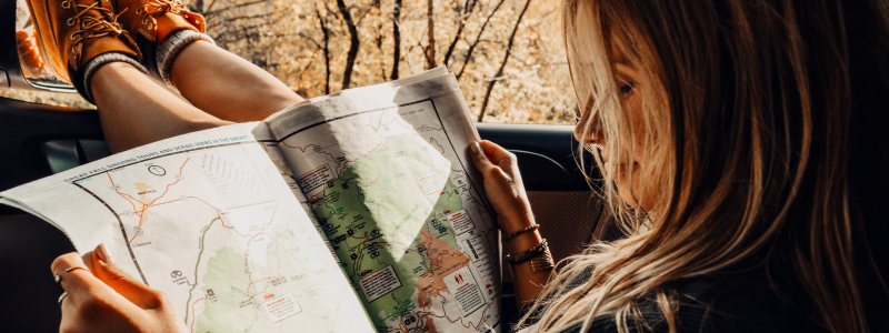 Woman looking at a map with her feet out a car window