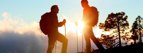 Silhouette of a couple hiking in a mountain range 