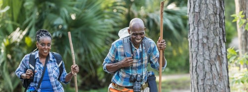 Couple hiking through a forest with hiking gear