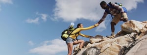 Man helping woman hike up a rock