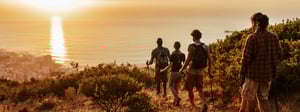 Group of friends hiking towards the ocean and sunset