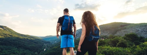 Couple hiking through a mountain range with backpacks