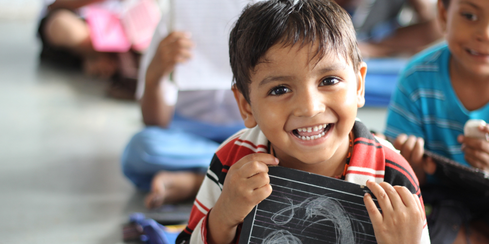 Child holding a chalkboard at school