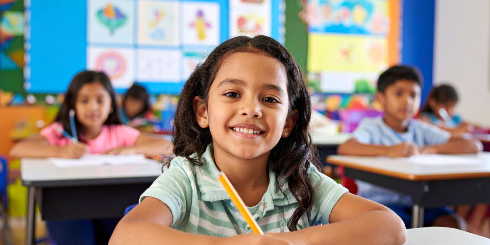 Child writing in her book while smiling at school