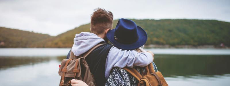 Couple facing away from the camera towards a lake hugging