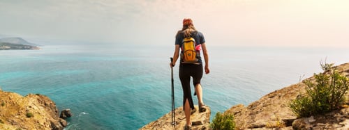 Woman standing on a cliff looking at the ocean