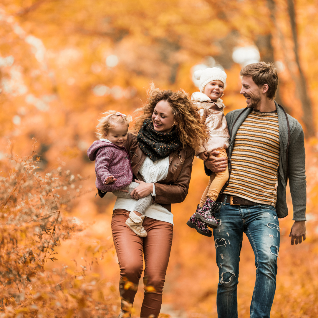 Family of 4 with mother, father and 2 kids walking in fall leaves