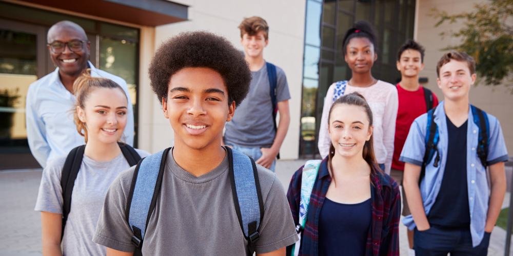Group of high school students smiling with backpacks on