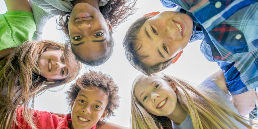 Middle school students standing in a circling with their heads in and smiling