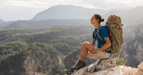 Man sitting on a rock looking into a mountain range