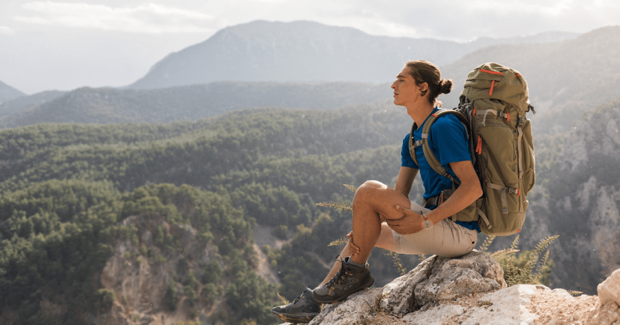 Man sitting on a rock looking into a mountain range