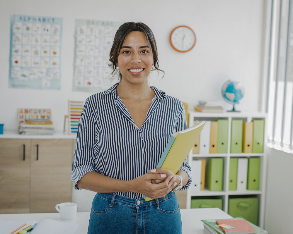 Teacher holding books and smiling