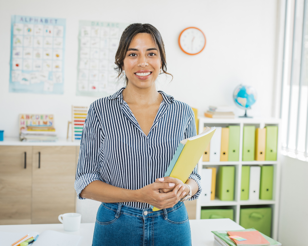 Teacher holding books and smiling