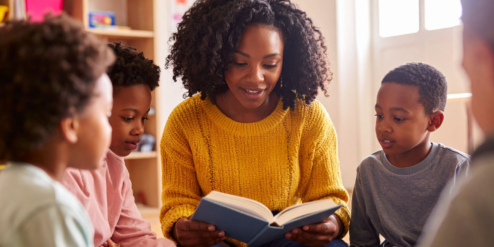 Teacher reading a book to a group of students
