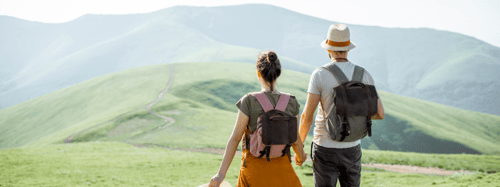 Couple holding hands and walking through a mountain range together