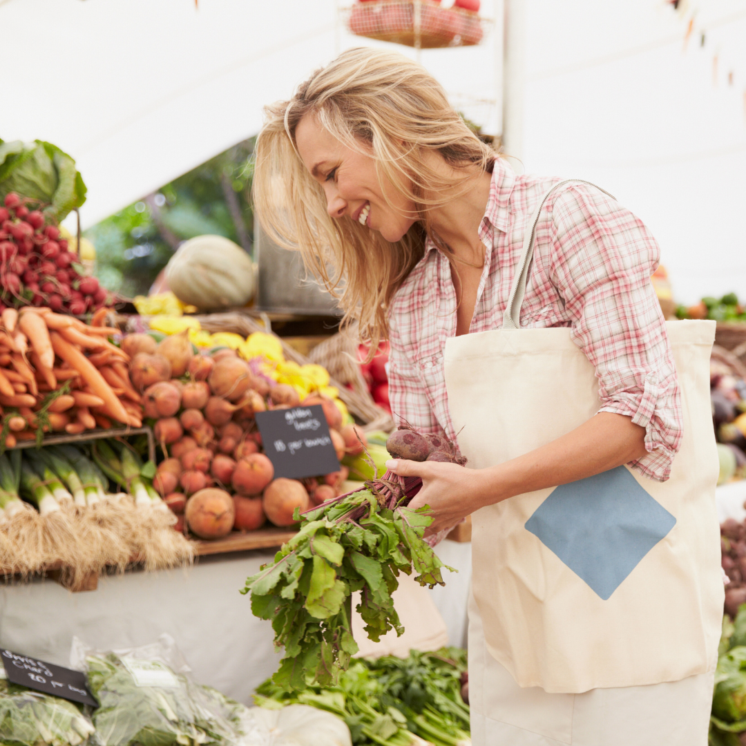 Woman walking around a farmer's market picking vegetables
