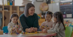 Teacher sitting with students and smiling