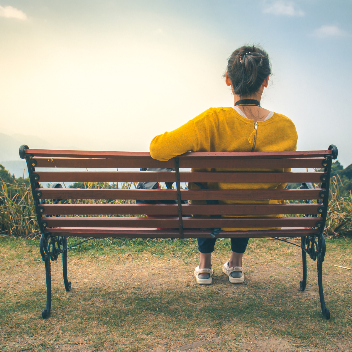 Woman sitting on a bench looking into a field