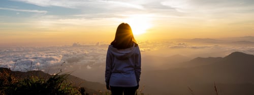 Woman standing in a mountain range looking into the horizon