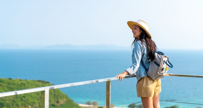 Woman standing on a balcony looking out at the ocean and smiling