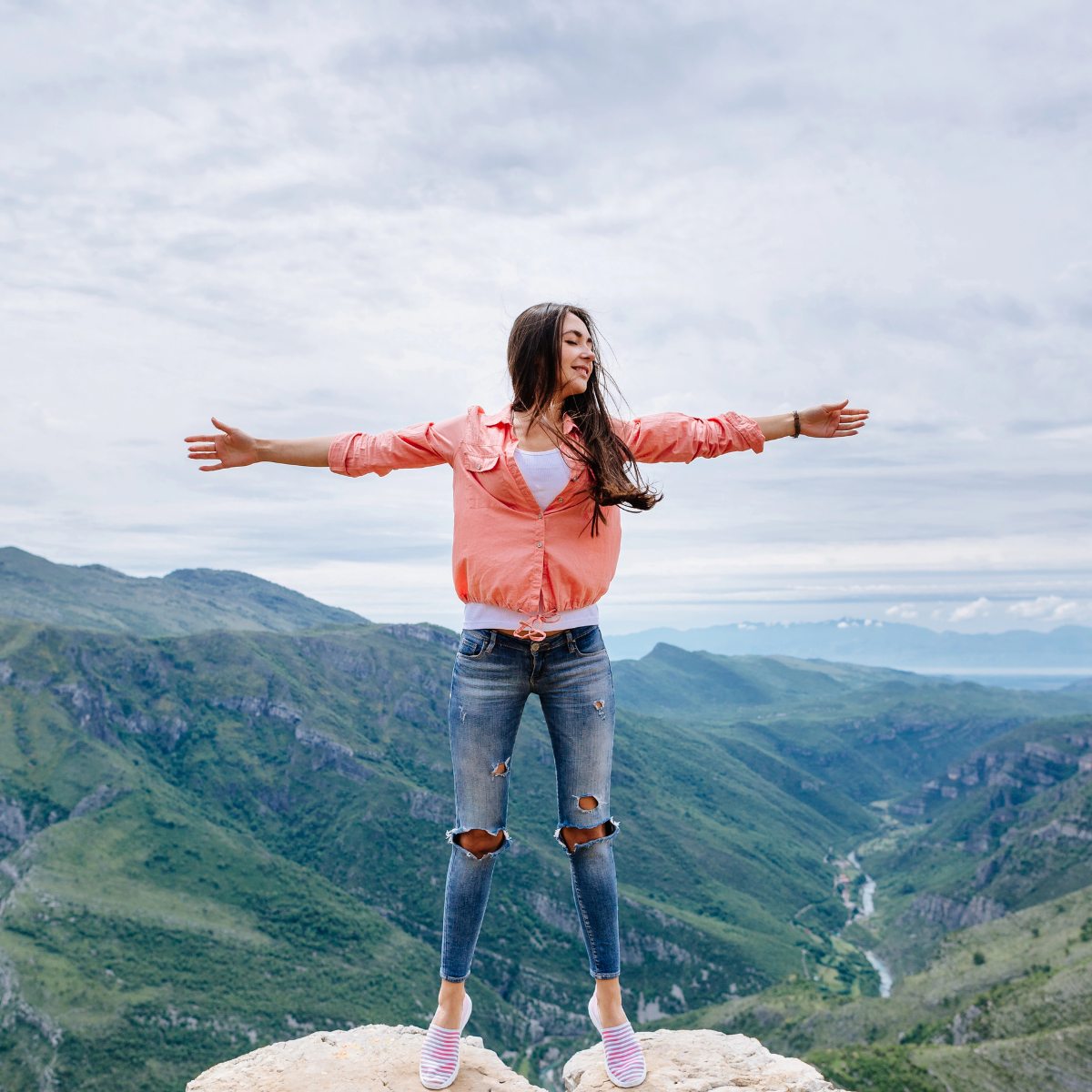 Woman with her hands out and a mountain range in the background