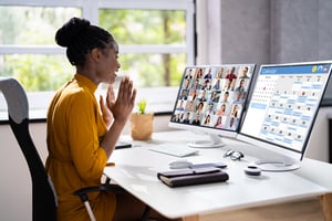 Woman sitting at a desk looking at a computer on a Zoom call