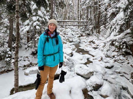 Woman standing amongst rocks covered in snow