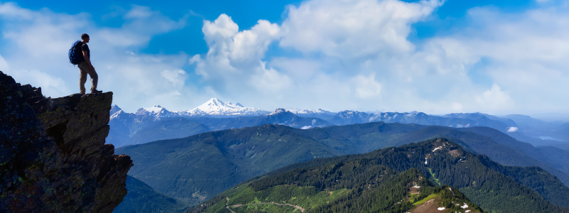 Cath lab tech on a hike standing on a rock in a mountain range