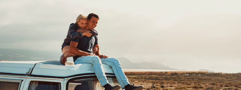 Couple hugging on a car rooftop 