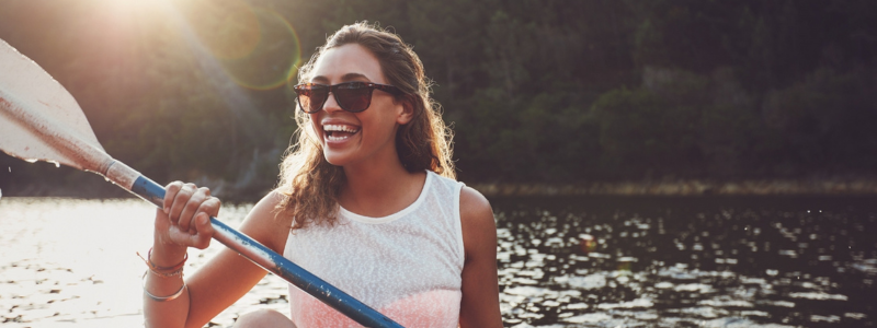 Woman kayaking down a river and smiling