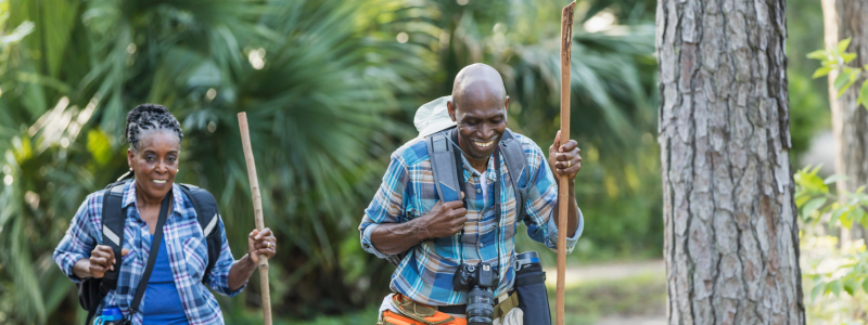 Couple hiking through a forest with hiking gear