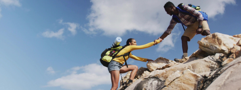 Man helping woman hike up a rock
