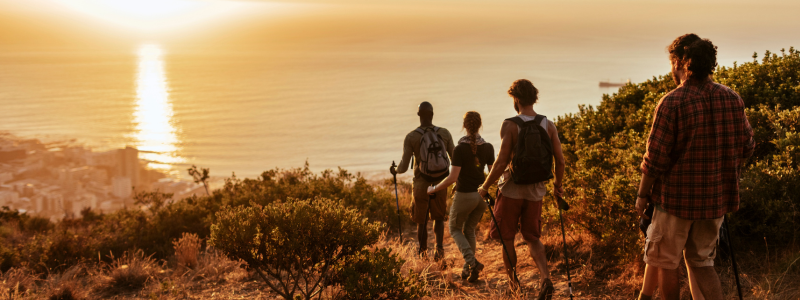 Group of friends hiking towards the ocean and sunset