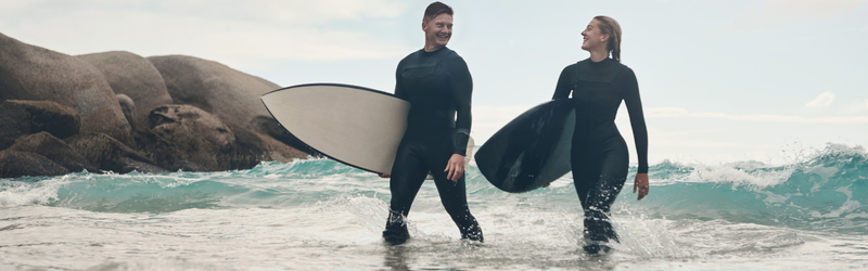 Couple holding surfboards walking out of the ocean