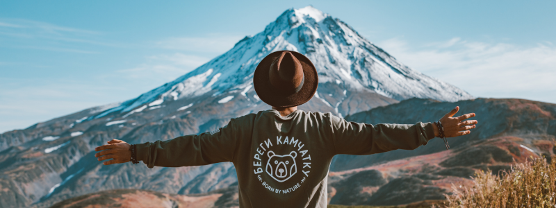 Man with his arms out facing away from the camera facing a mountain