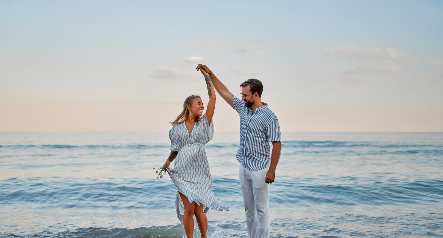 Man spinning woman while dancing on the beach