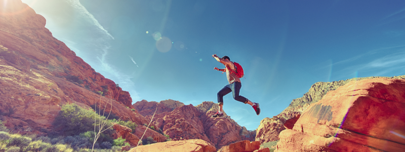 Woman jumping over red rocks